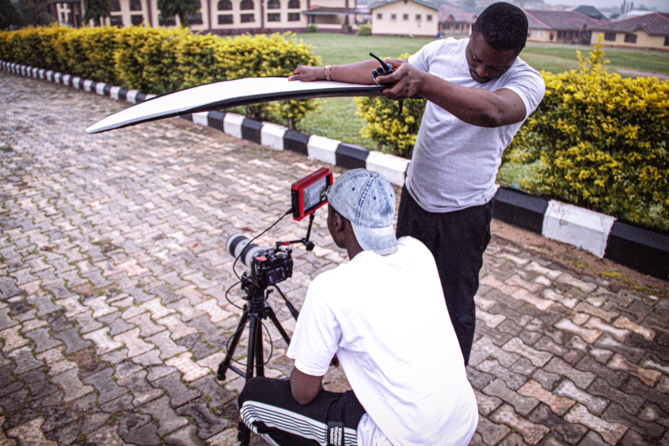 Oluwatobi Elijah holding a reflector over a camera operator on location